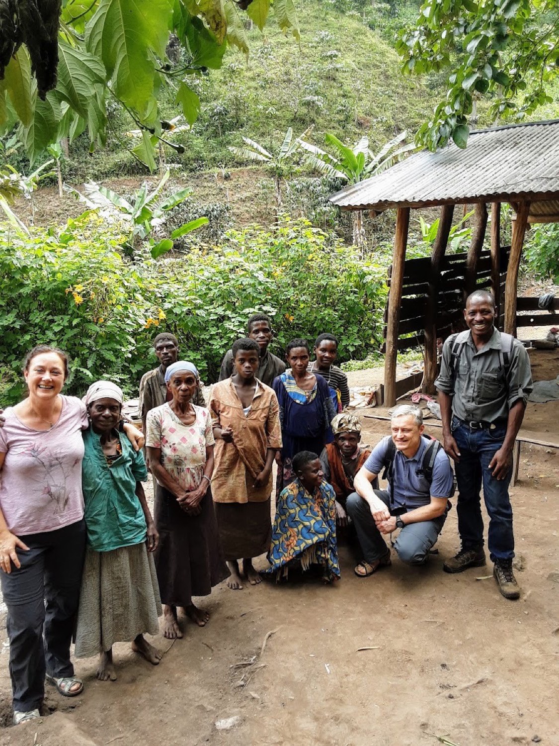 Guests standing with members of a local community during a village visit in the Rwenzori foothills